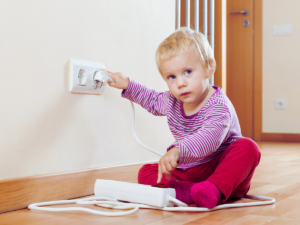 child attempting to plug surge protector into tamper-resistant outlet