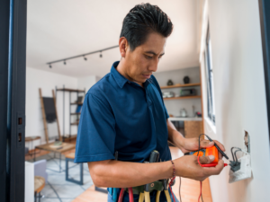 Electrician using multimeter to test a wall outlet
