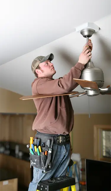 Electrician installing a residential ceiling fan during ceiling fan installation service