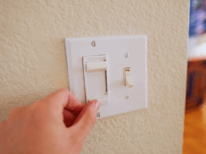 POV of man adjusting dimmer switch that controls his living room light fixtures