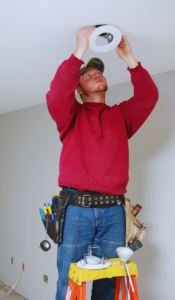 Electrician installing recessing lighting on existing old wiring