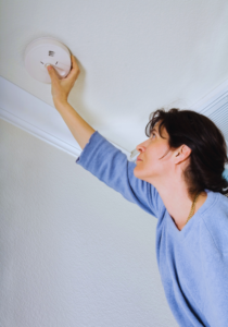 Homeowner inspecting smoke alarm